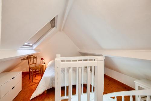 ein Schlafzimmer mit einem weißen Kinderbett im Dachgeschoss in der Unterkunft Invitation a la detente dans une charmante maison in Plévenon