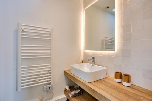 ein Badezimmer mit einem weißen Waschbecken und einem Spiegel in der Unterkunft Invitation a la detente dans une charmante maison in Plévenon