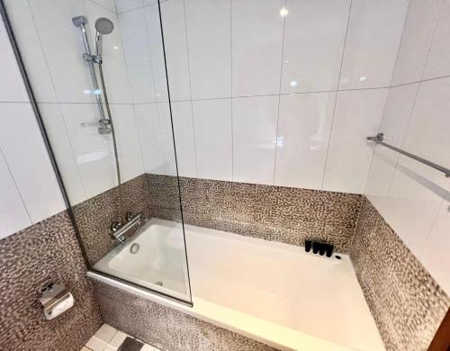 a bathroom with a tub with a glass door at Spirit Tower - 1BR Apartment - Allsopp&Allsopp in Dubai