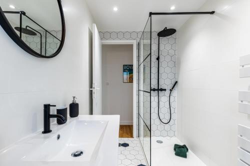 La salle de bains blanche est pourvue d'une douche et d'un lavabo. dans l'établissement L’Auguste - Appartement Terrasse, 450m de la plage, à Royan