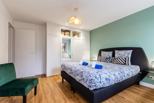- une chambre avec un grand lit et une chaise verte dans l'établissement L’Auguste - Appartement Terrasse, 450m de la plage, à Royan