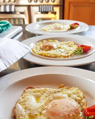 three plates of food on a table with eggs and vegetables at Helicon Muses Friendly Mountain B&B Guesthouse in Evangelístria