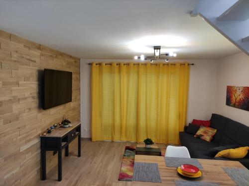 ein Wohnzimmer mit einem Sofa und einem TV in der Unterkunft Appartement duplex indépendant, dans maison. in Tresserves