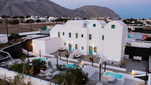an aerial view of a white house with mountains in the background at Santa Irina Luxury Sunny Lofts in Perivolos
