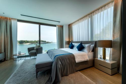 a bedroom with a large bed and a large window at Nurai Water Villa By Luxury Explorers Collection in Abu Dhabi