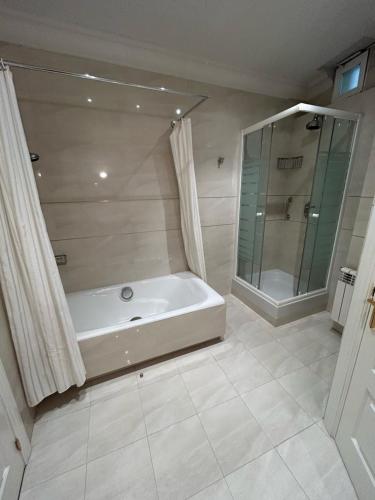 a white bathroom with a tub and a shower at PdV rooms in Madrid