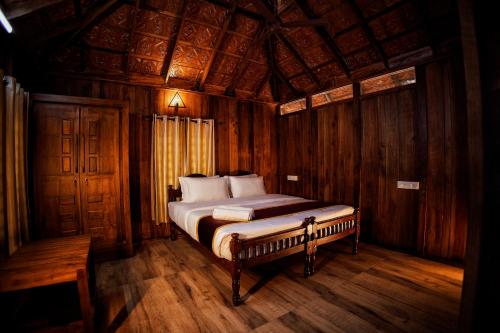 1 dormitorio con 1 cama en una habitación de madera en Mahout Resort Wayanad - An Experiential Jungle Stay with Waterfall, en Kalpetta