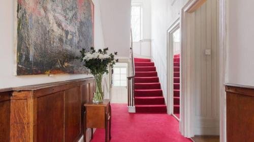 a hallway with a vase of flowers on a table and stairs at Spacious 4 bed, Central Camden in London