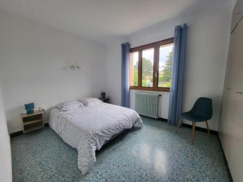 ein Schlafzimmer mit einem Bett, einem Stuhl und einem Fenster in der Unterkunft Le Cèdre in Les Vans