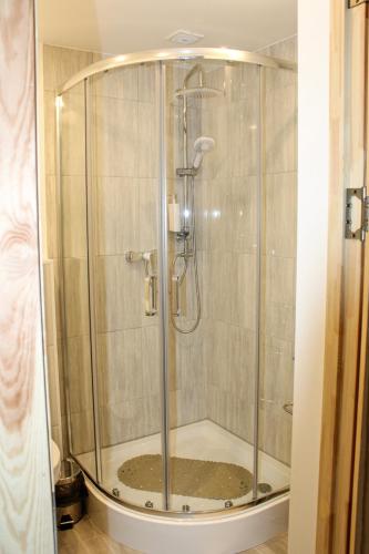 a shower with a glass enclosure in a bathroom at Dzintara apartamenti in Kuldīga