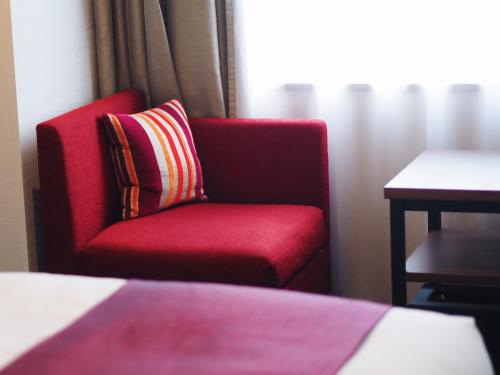 a red chair with a striped pillow in a hotel room at Hotel Intergate Tokyo Kyobashi in Tokyo