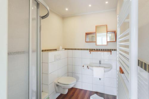 a white bathroom with a toilet and a sink at Buedlfarm-NordOst in Sahrensdorf