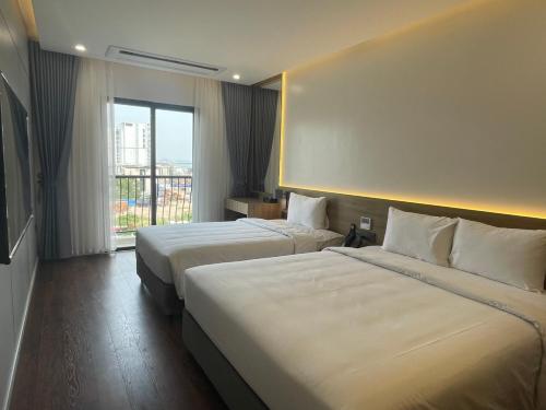 um quarto de hotel com duas camas e uma grande janela em Elite Hotel em Ha Long