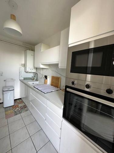a kitchen with white cabinets and a microwave at T3 Moulin à vent proche UPVD in Perpignan