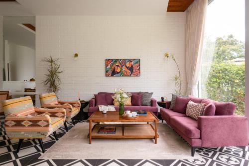 a living room with purple couches and a table at La Meira 3BHK Villas in Assagao with Private Pool, Garden, Caretaker, Kitchen & Security in Vagator