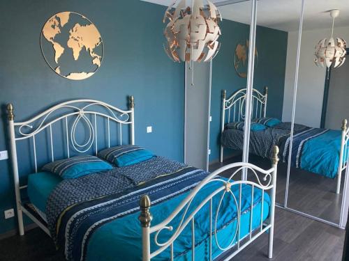 - une chambre avec 2 lits aux murs bleus et un miroir dans l'établissement Maison de charme, à Saint-Avé