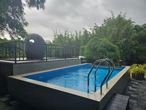 a swimming pool with two metal rails next to a building at Athirapally Green Trees in Athirappilly