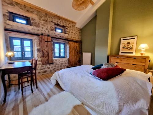 a bedroom with a bed and a desk and windows at GITE LA MENOU in Usson-en-Forez
