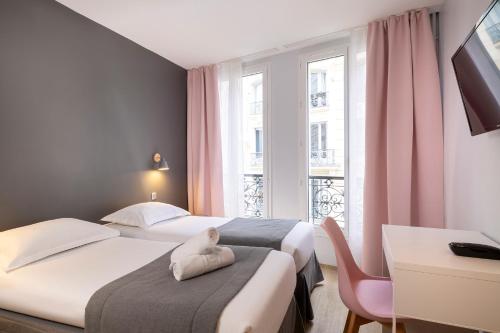 パリにあるパリ ルジャンドルのベッド2台、デスク、窓が備わるホテルルームです。