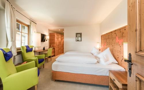 a hotel room with a bed and two chairs at Mirabell Dolomites Hotel - Luxury Ayurveda & Spa in Valdaora