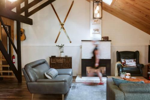 a person walking through a living room with a fireplace at Le Grizzli Orford in Orford