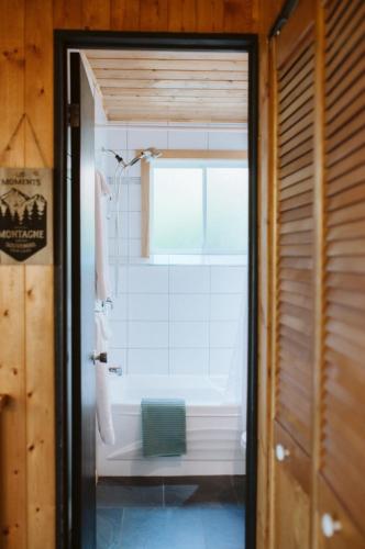 a bathroom with a bath tub and a window at Le Grizzli Orford in Orford