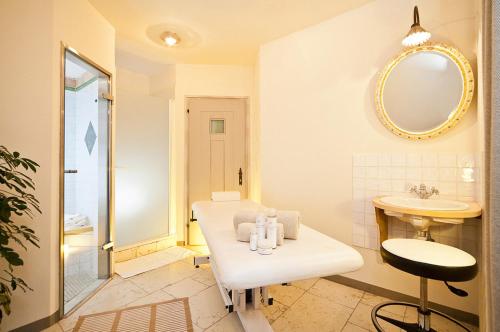 a white bathroom with a sink and a mirror at Mirabell Dolomites Hotel Luxury Ayurveda & Spa in Valdaora