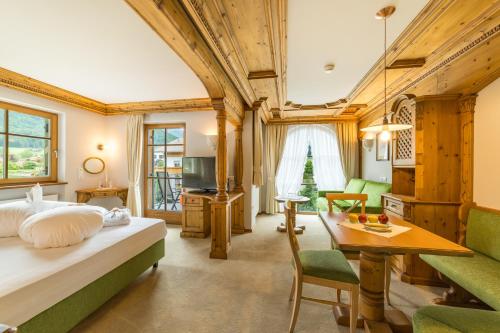 a bedroom with a bed and a living room at Mirabell Dolomites Hotel Luxury Ayurveda & Spa in Valdaora