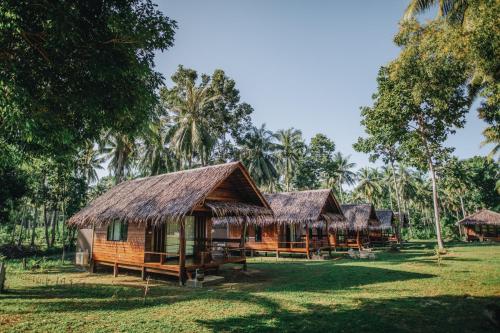 a group of huts in a field with trees at COCO Canopy Boutique Resort in Ko Jum