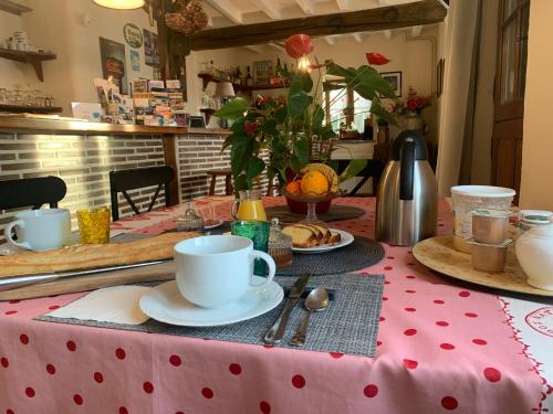 einem Tisch mit einem roten Tischtuch aus Polyka und Kaffeetassen in der Unterkunft Les Logis du Breuil in Marchéville