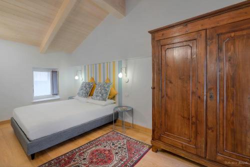 a bedroom with a bed and a large wooden cabinet at Casa nel Vicolo - Storie e Dimore in Chieri