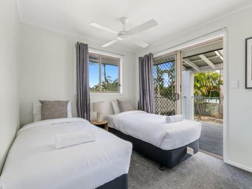 two beds in a room with a window at Luxury 5BR Retreat Family house with Pool in GC in Gold Coast