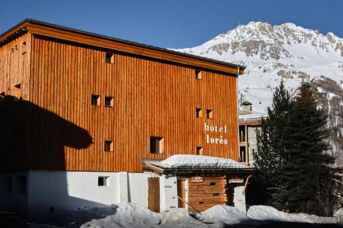 a building in the snow with a mountain in the background at Hôtel les Lorès in Val-d'Isère