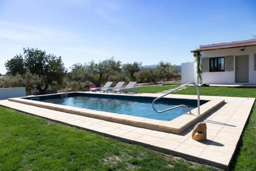 a swimming pool with a teddy bear sitting in the grass at Santolina - Casa Rural en l'Ampolla con piscina privada, jardín y barbacoa - Deltavacaciones in L'Ampolla