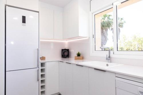 a white kitchen with a sink and a window at Aimar - Casa en Deltebre con jardín, piscina privada y barbacoa - Deltavacaciones in Deltebre