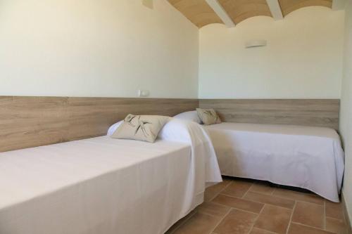 two beds in a room with white walls at Santolina - Casa Rural en l'Ampolla con piscina privada, jardín y barbacoa - Deltavacaciones in L'Ampolla