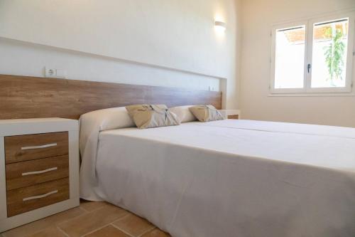a bedroom with a large white bed and a window at Santolina - Casa Rural en l'Ampolla con piscina privada, jardín y barbacoa - Deltavacaciones in L'Ampolla