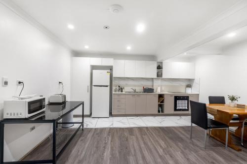 a white kitchen with a table and a microwave at Spacious Sandy Bay Apartment in Sandy Bay