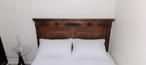 a bed with a wooden headboard and white sheets at Omar Apartments in Casablanca