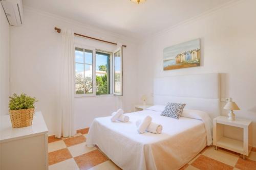 a white bedroom with a bed and a window at Villa Marques by Villa Plus in Cala'n Porter