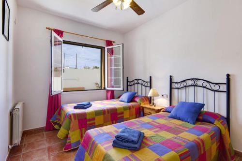 two beds in a room with a window at Villa Maria Del Mar by Villa Plus in Cala'n Porter