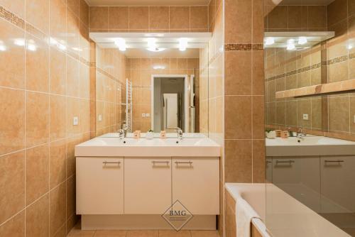 une salle de bain avec deux lavabos, un miroir et une baignoire dans l'établissement Disneyland Résidence Bmyguest, à Serris