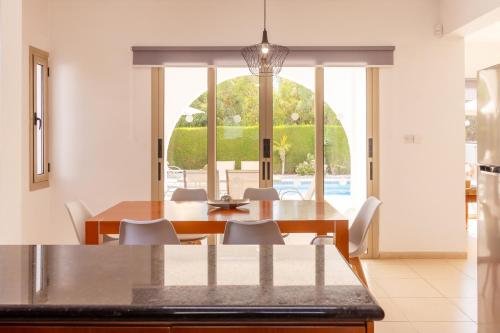 a dining room with a table and chairs and a large window at Villa Shanta in Peyia
