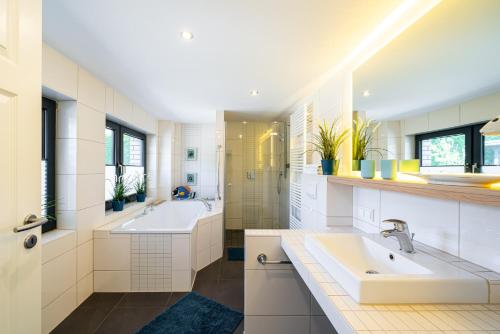 a bathroom with two sinks and two mirrors at Ferienhaus Landlust - Erholung mit Fasssauna und Whirlpool nahe Binz! in Zirkow