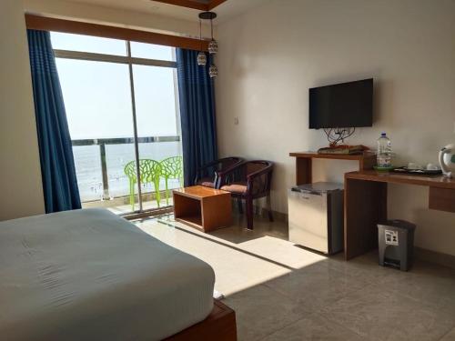 Schlafzimmer mit einem Bett, einem TV und einem Fenster in der Unterkunft Hotel Sea Moon in Cox's Bazar