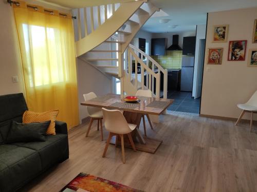 ein Wohnzimmer mit einem Tisch und einer Treppe in der Unterkunft Appartement duplex indépendant, dans maison. in Tresserves