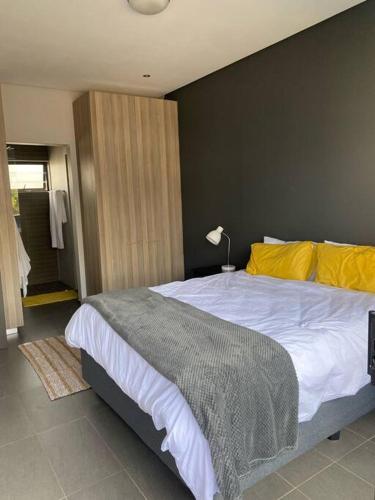 a bedroom with a large bed with a yellow pillow at The Blues in Pretoria