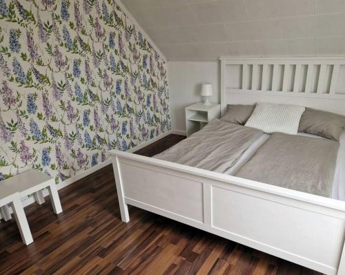 a bedroom with a white bed with a floral wallpaper at Ferienhaus am Waldrand in Lillhärdal