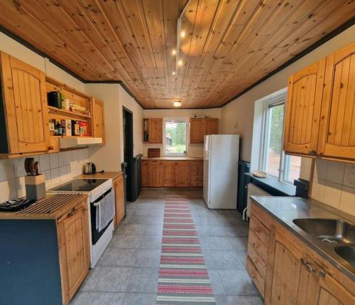 - une cuisine avec des placards en bois et un réfrigérateur blanc dans l'établissement Ferienhaus am Waldrand, à Lillhärdal