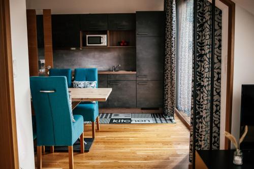 a kitchen with a wooden table and blue chairs at Alpenhotel & Aparthotel Lanz in Hohentauern